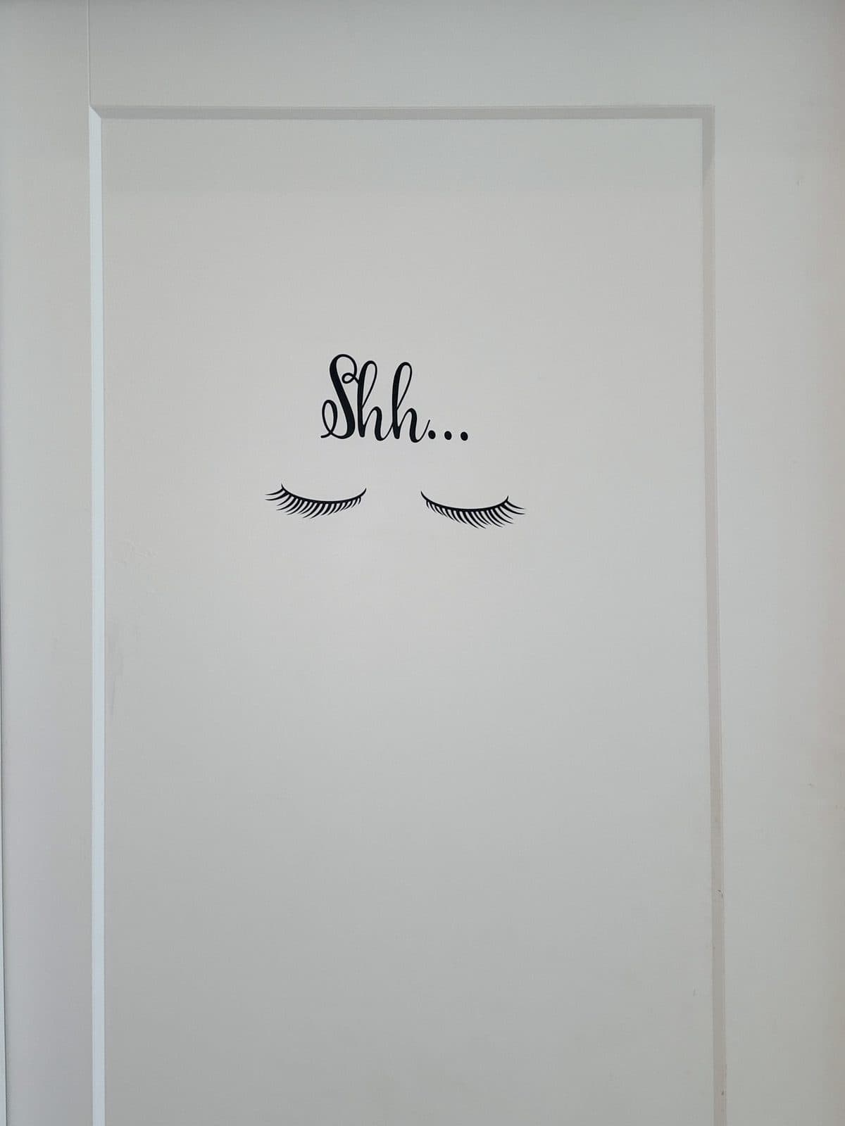 Une porte de salle de soin avec le mot Shh et deux yeux fermés