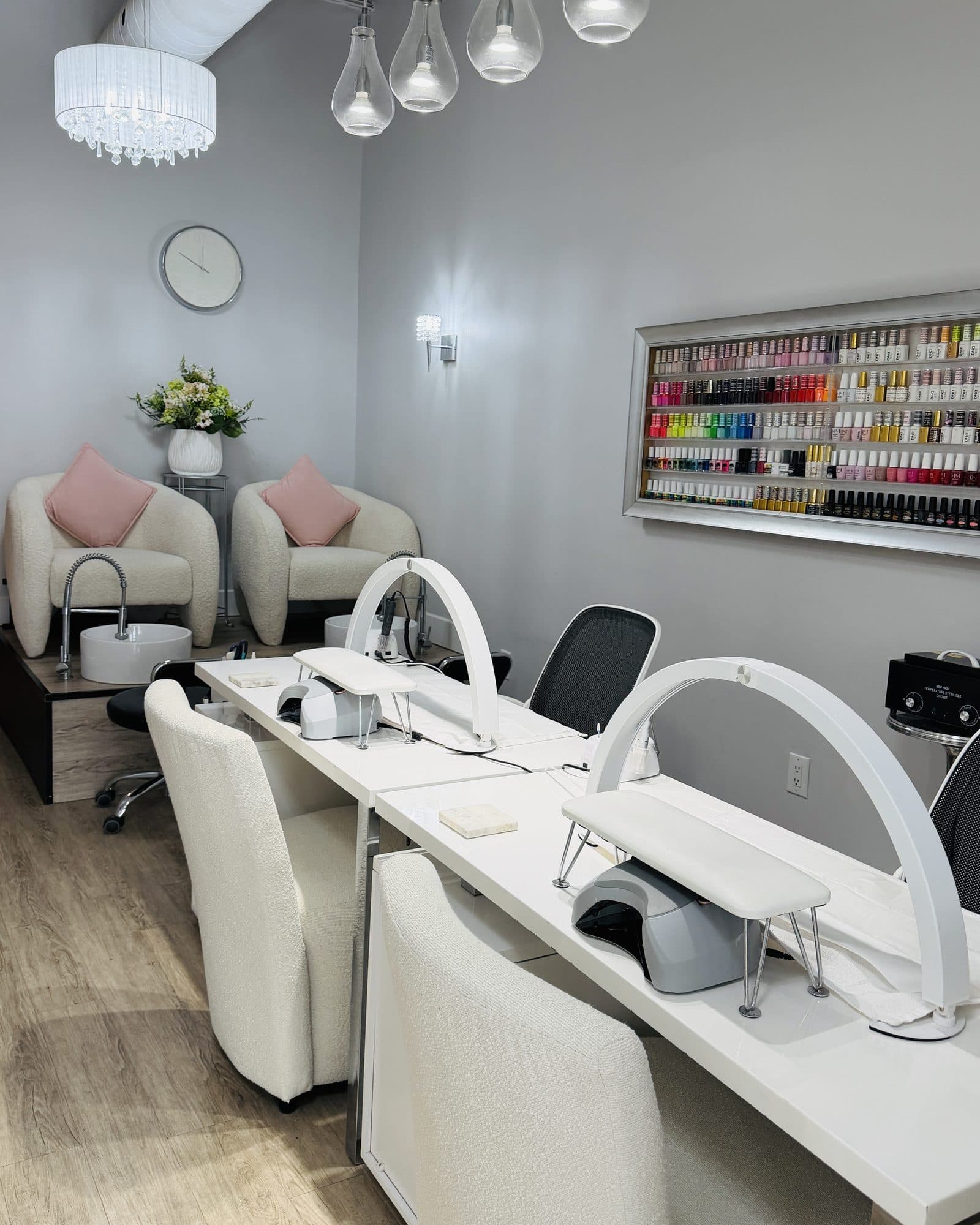 The nail stations with their arched lamps, in front of the wall of polish